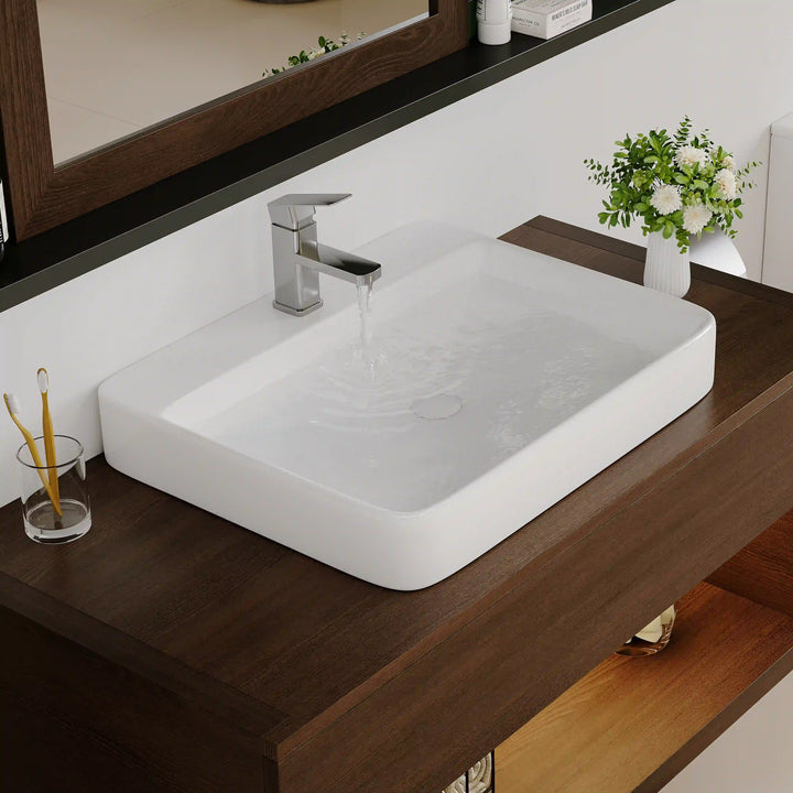 White ceramic rounded vessel sink with flowing water chrome faucet