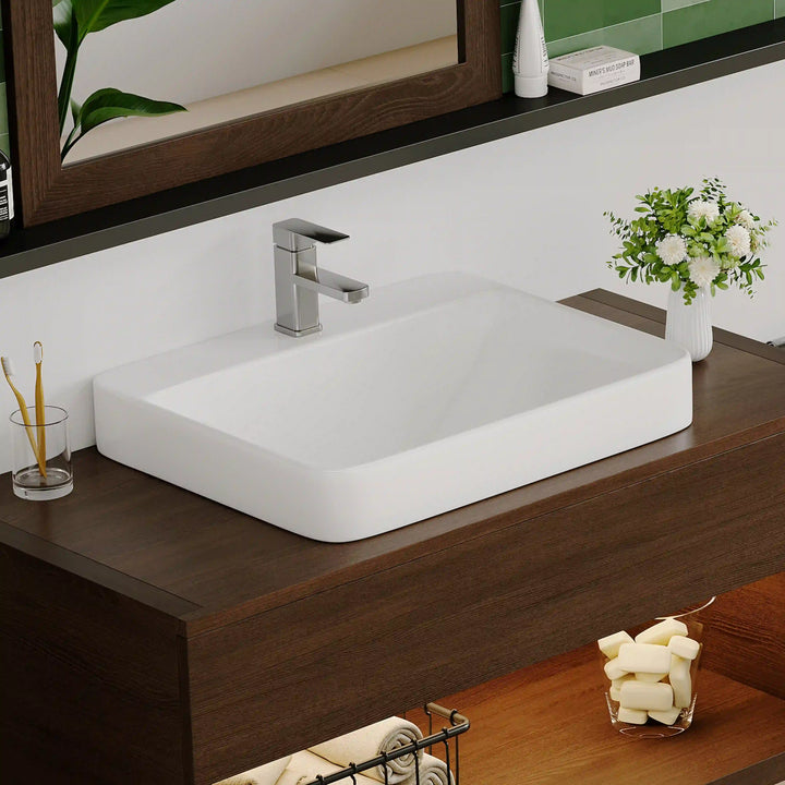 White ceramic rounded rectangular vessel sink with modern chrome faucet