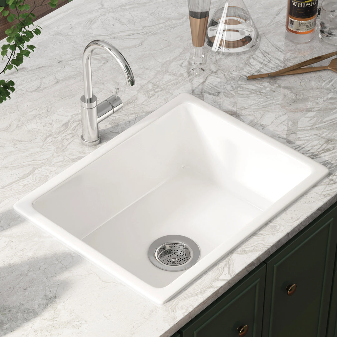 White undermount single bowl kitchen sink with smooth solid surface and rear drain opening.