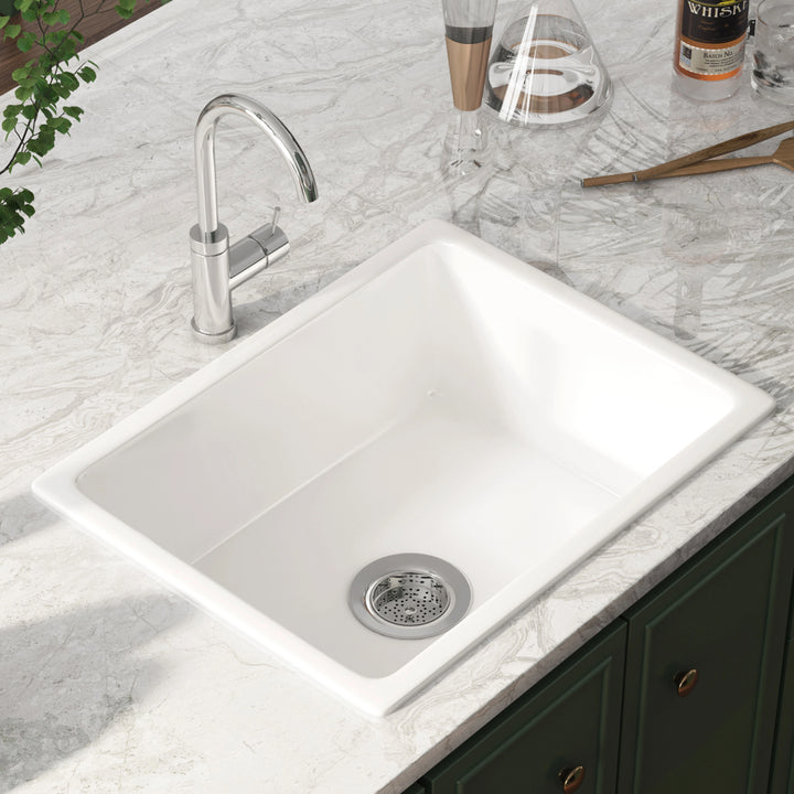 White undermount single bowl kitchen sink with smooth solid surface and rear drain opening.