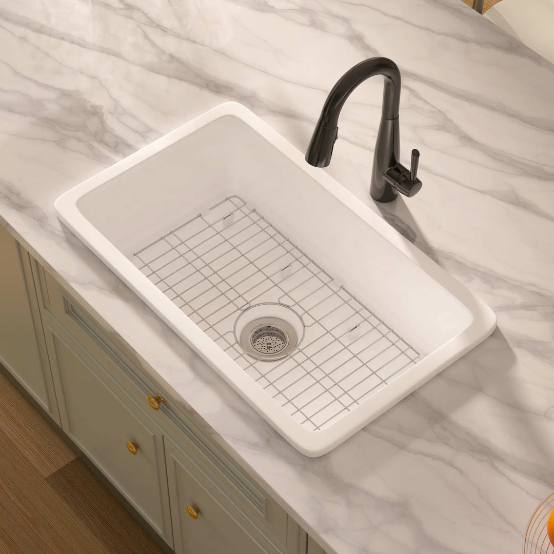 White rectangular drop-in fireclay kitchen sink with black faucet and grid