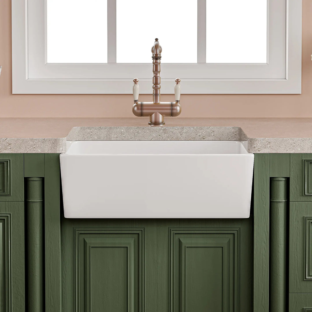 White fireclay apron front farmhouse kitchen sink with antique faucet