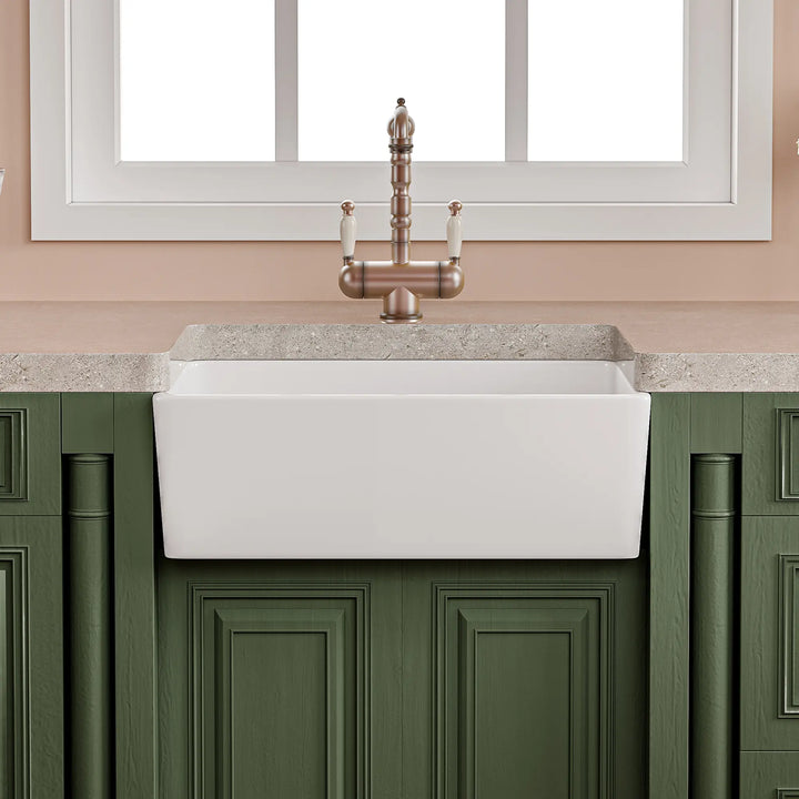 White fireclay apron front farmhouse kitchen sink with antique faucet