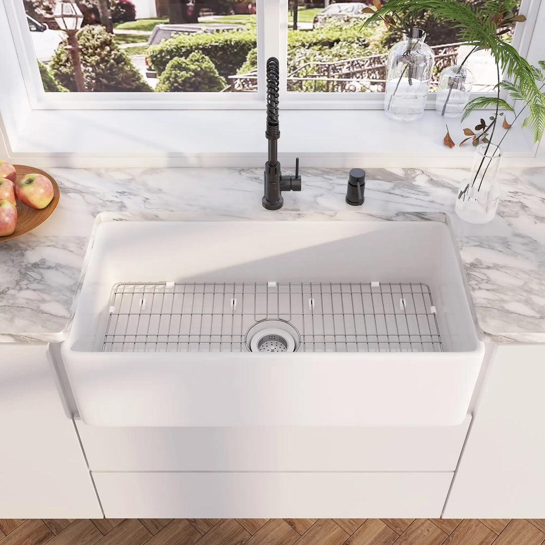 White fireclay farmhouse kitchen sink with stainless steel bottom grid, matte black pull down faucet