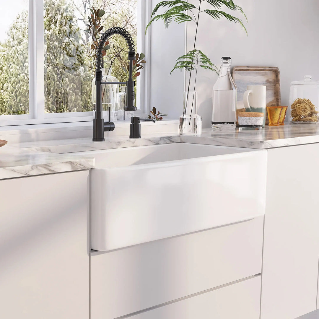 White fireclay apron front farmhouse kitchen sink paired with matte black spring pull-down faucet