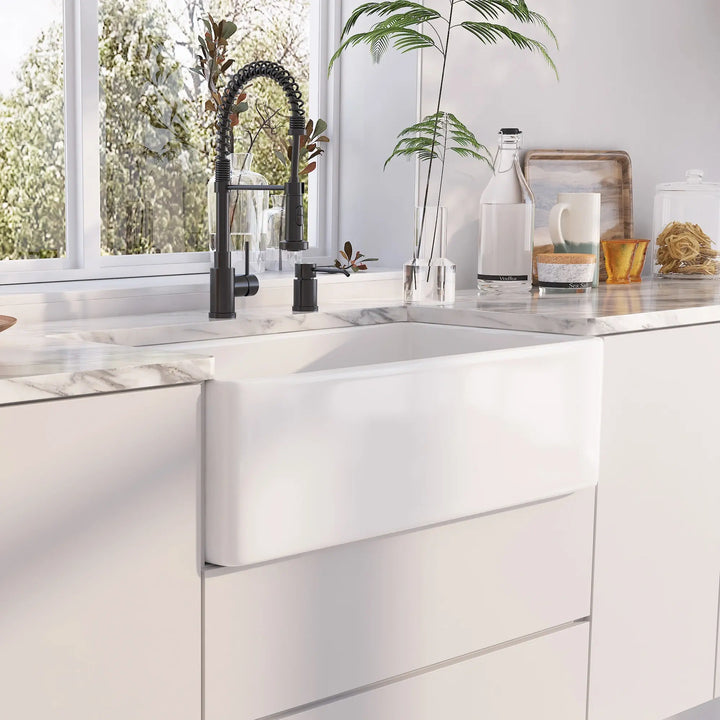 White fireclay apron front farmhouse kitchen sink paired with matte black spring pull-down faucet