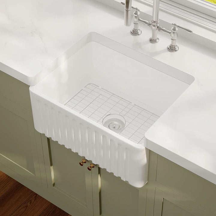 White ceramic farmhouse sink with fluted apron and bottom grid