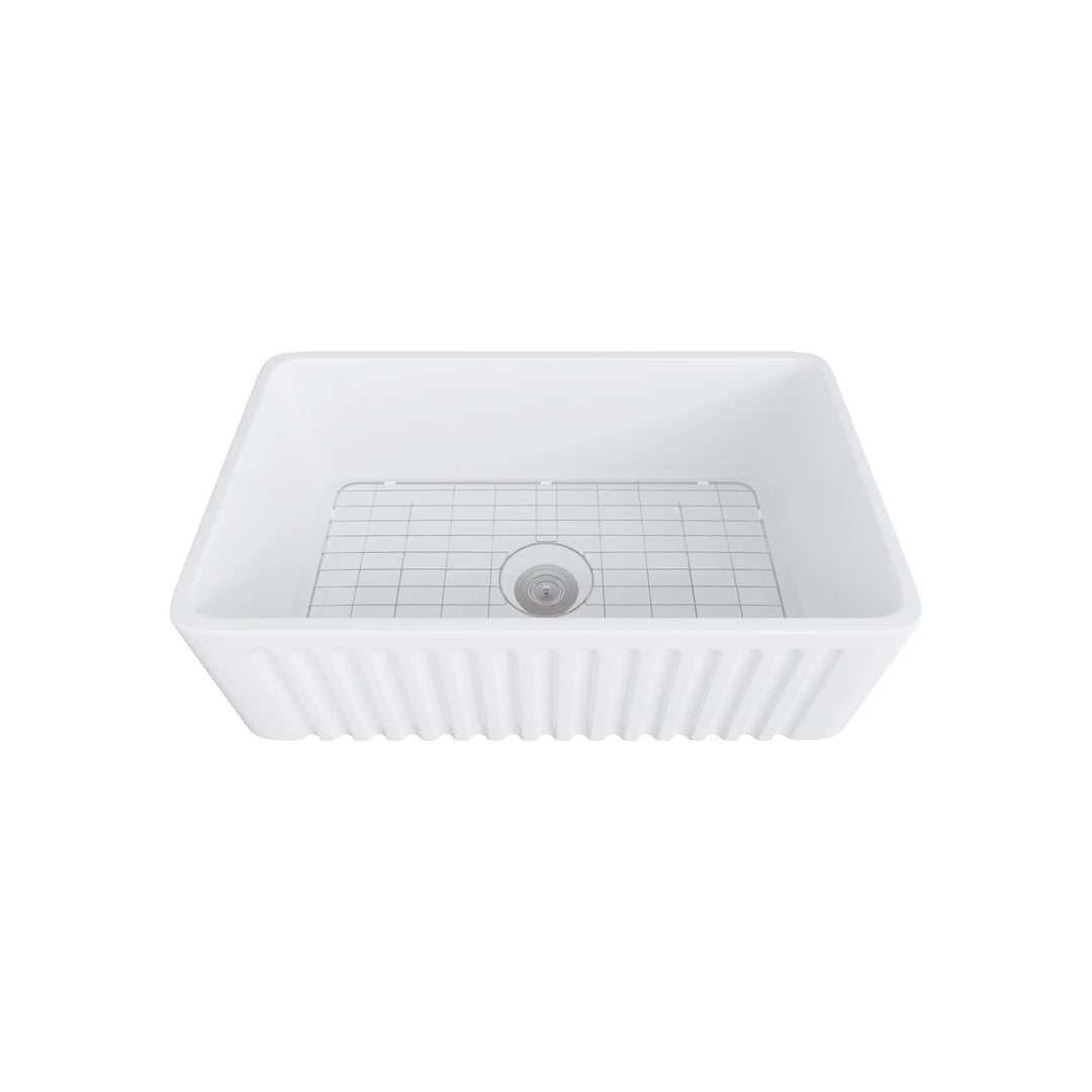 White fluted apron front fireclay farmhouse sink equipped with stainless steel bottom grid