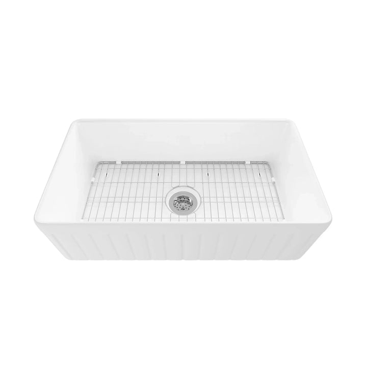 White fireclay single bowl farmhouse sink with fluted apron and stainless steel bottom rack