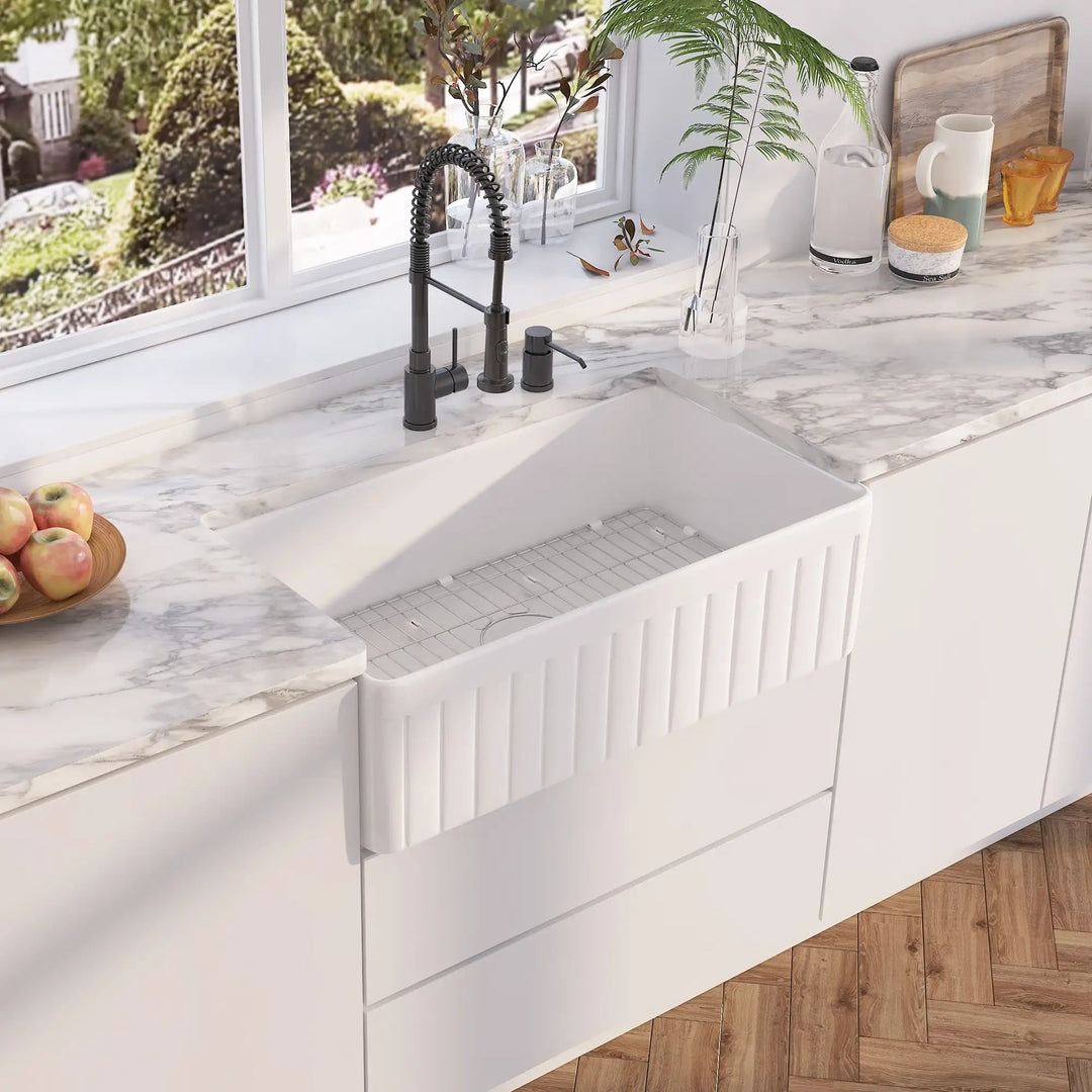 White fireclay single bowl farmhouse sink with fluted apron and stainless steel sink rack