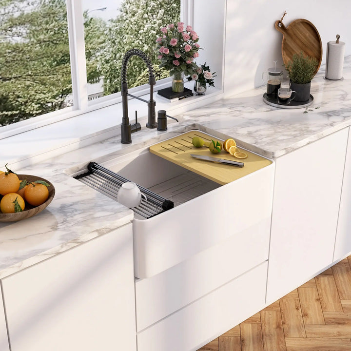 White fireclay single farmhouse sink with roll-up drying rack and bamboo cutting board