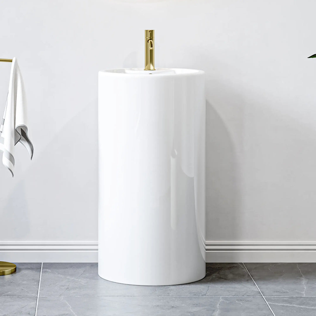 White cylindrical pedestal sink with gold single-hole faucet