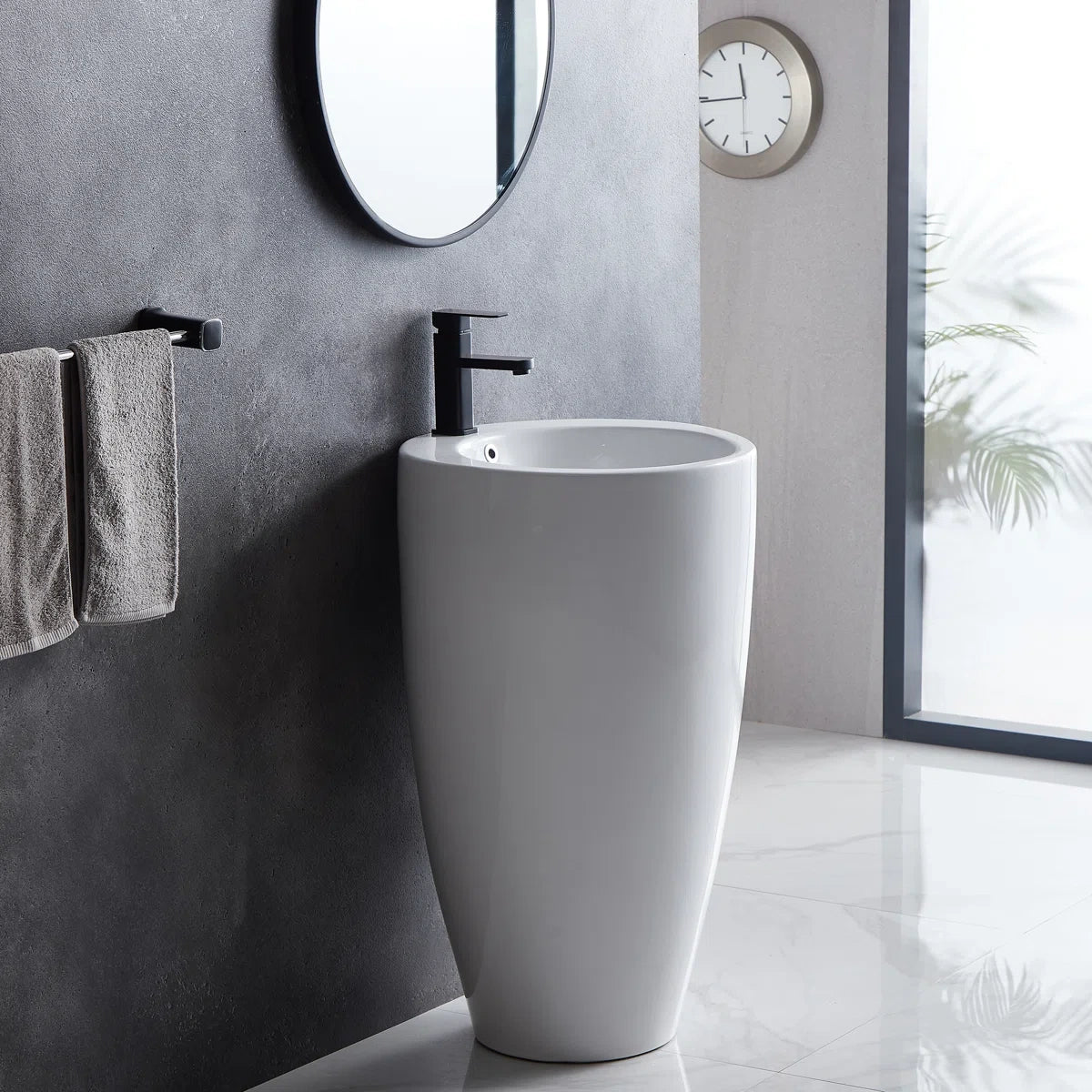 White freestanding pedestal sink with round basin and black faucet