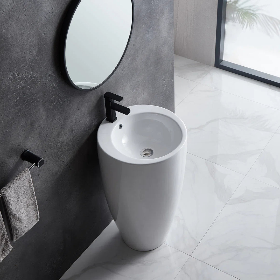 White freestanding pedestal sink with round basin and black faucet