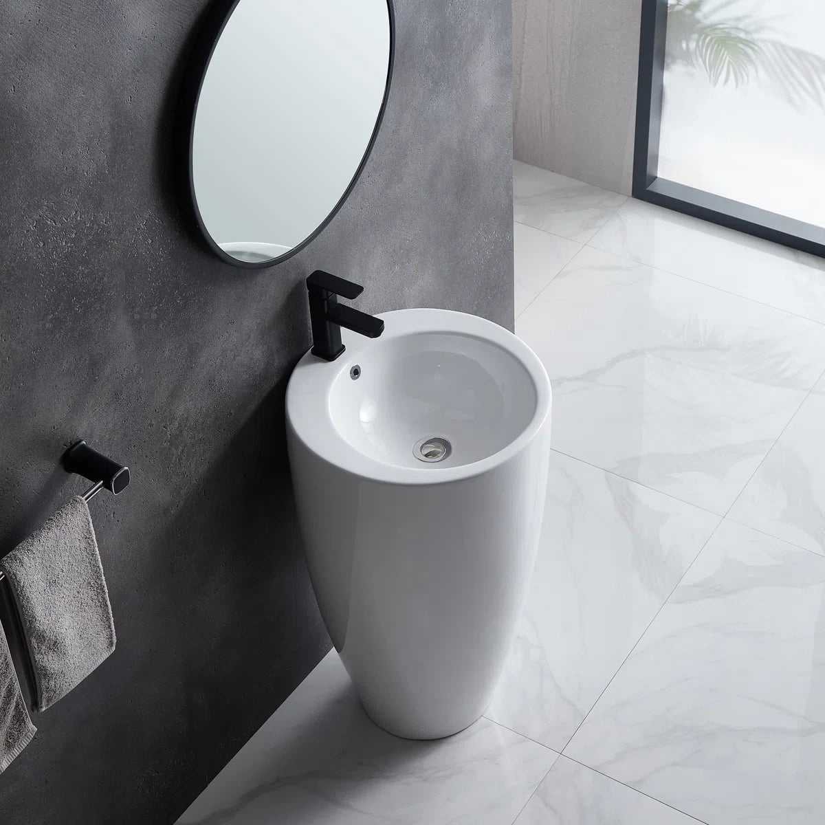 White freestanding pedestal sink with round basin and black faucet