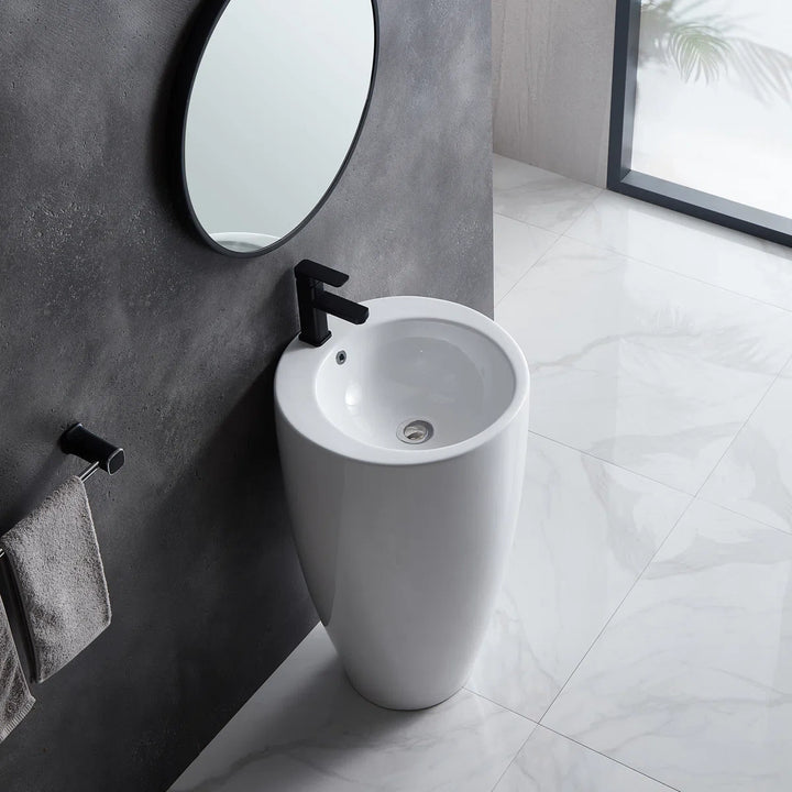 White freestanding pedestal sink with round basin and black faucet