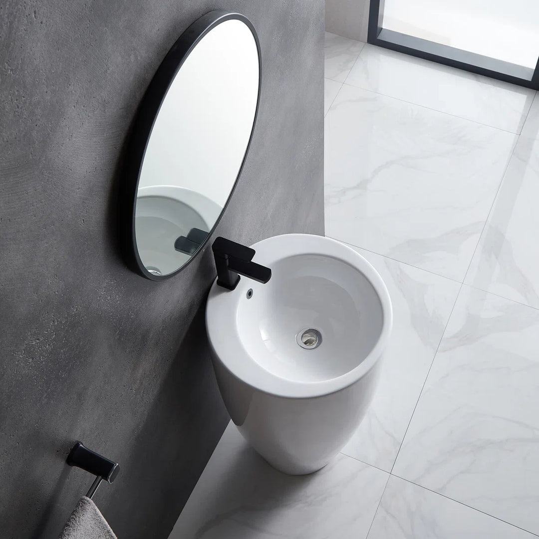 White freestanding pedestal sink with round basin and black faucet