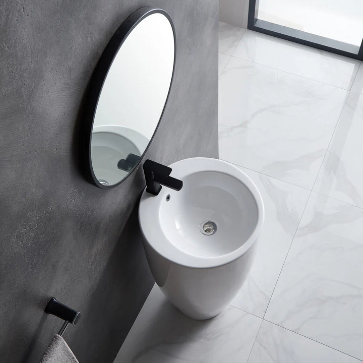 White freestanding pedestal sink with round basin and black faucet