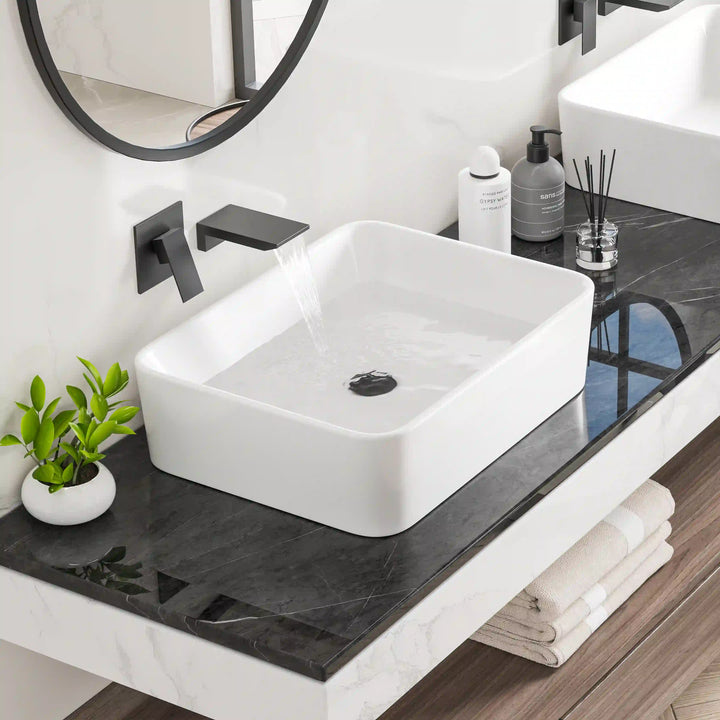 White rectangular ceramic countertop vessel sink with matte black wall-mounted faucet