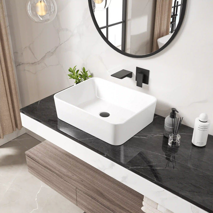 White rounded rectangular ceramic vessel sink with matte black wall faucet