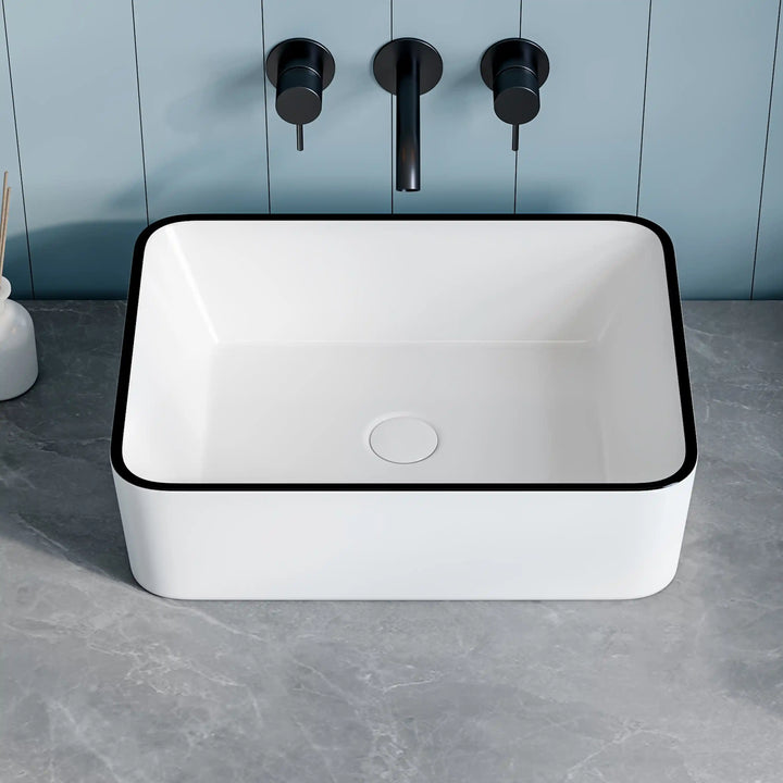 White rectangular ceramic vessel sink with thin black edge and matte black wall faucet set