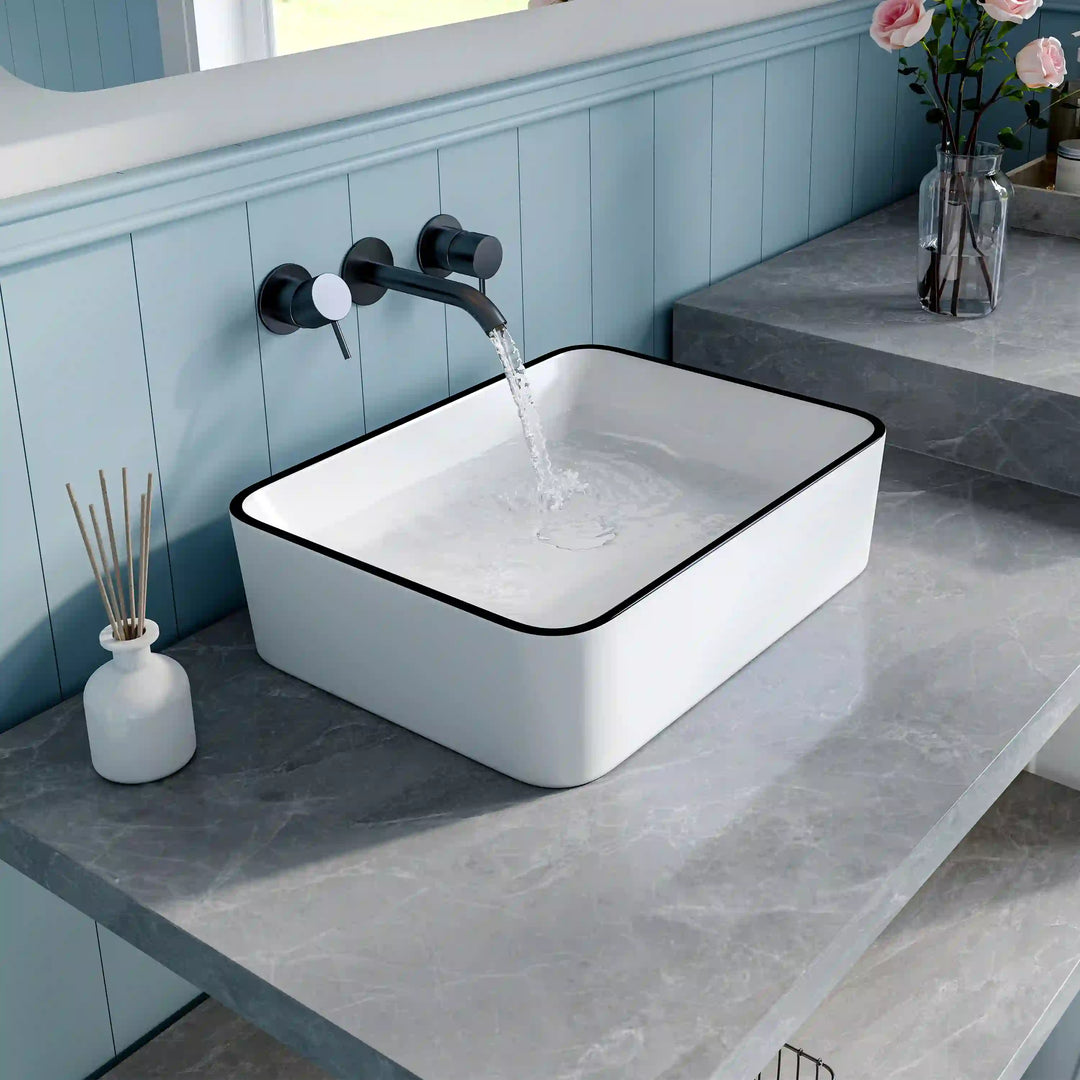 White square ceramic vessel sink with thin black rim and matte black wall faucet