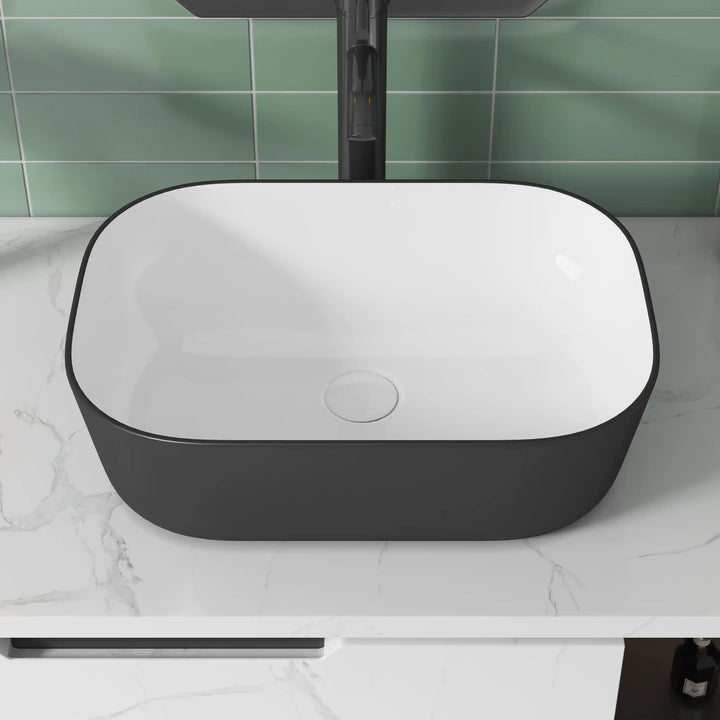 Matte black exterior white interior rectangular ceramic vessel sink with rounded corners
