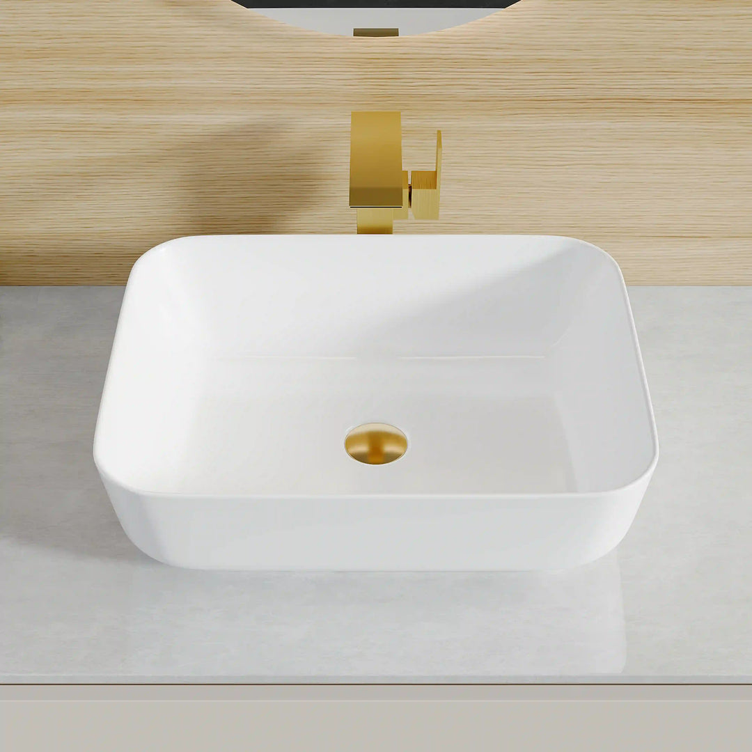 White square ceramic vessel sink with brushed gold wall-mounted faucet and gold drain