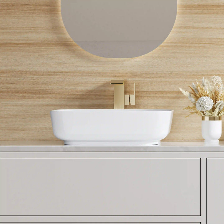 White rectangular ceramic vessel sink paired with brushed gold wall mounted faucet
