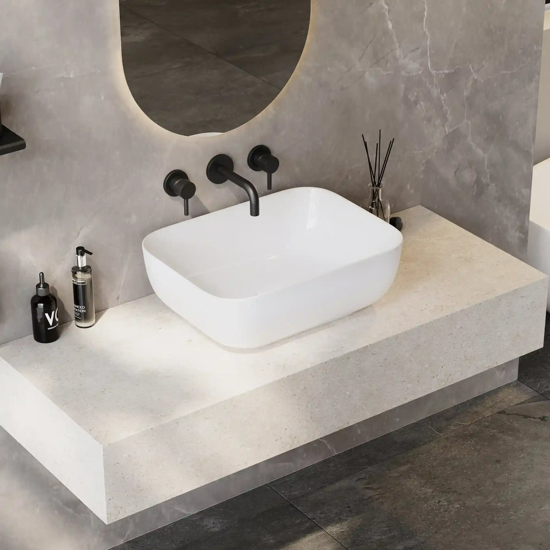 Matte white rounded square solid surface vessel sink with curved matte black three-hole wall faucet