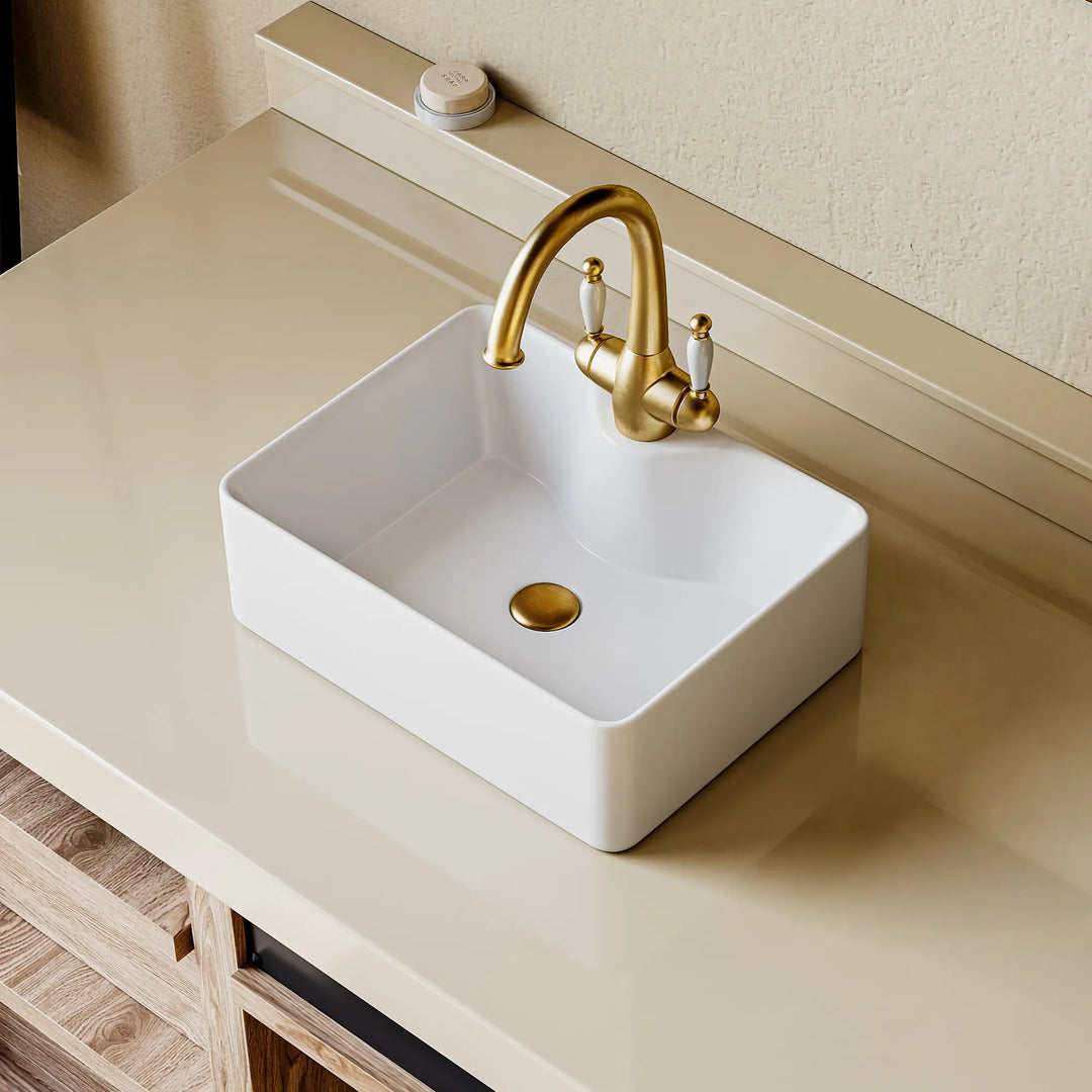 Eridanus white rectangular ceramic vessel sink with gold classical bridge faucet.