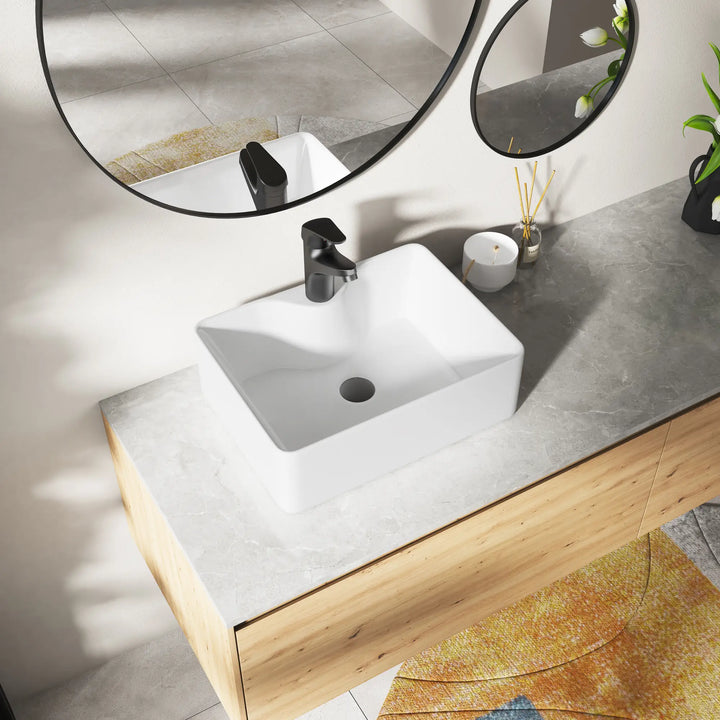 Eridanus white rectangular ceramic vessel sink with black faucet.