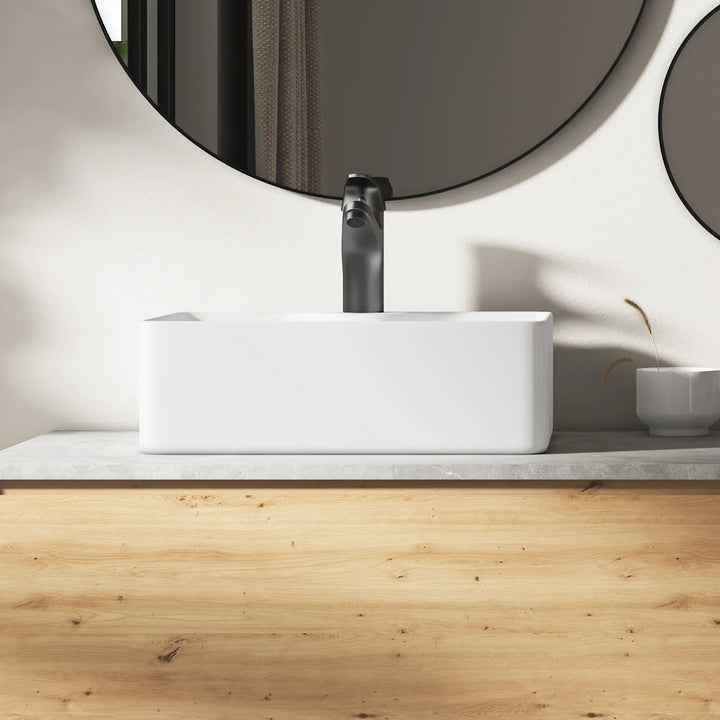 Eridanus white rectangular ceramic vessel sink with black faucet.