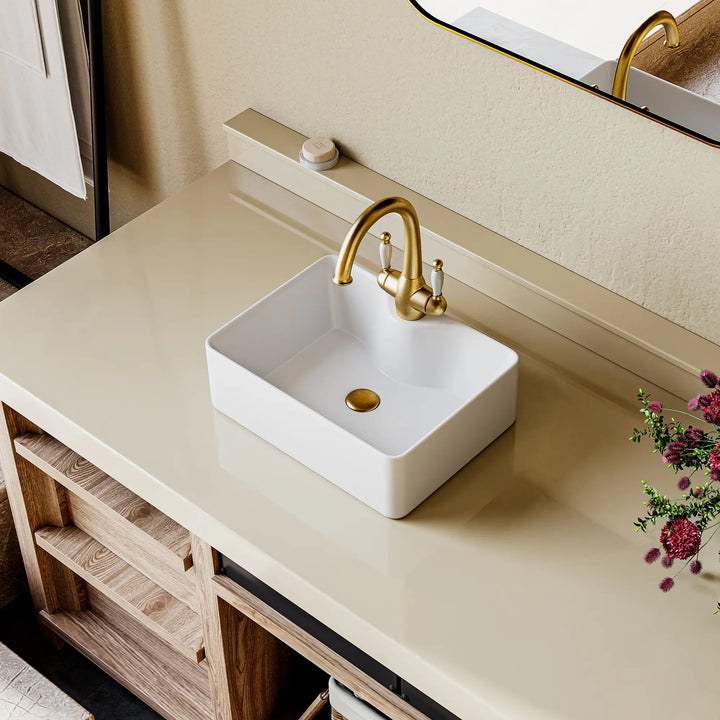 Eridanus white rectangular ceramic vessel sink with gold classical bridge faucet.