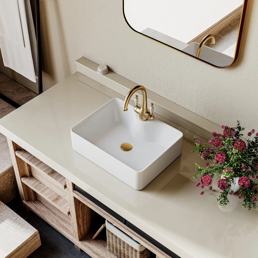White rectangular ceramic vessel sink with gold faucet, front view.