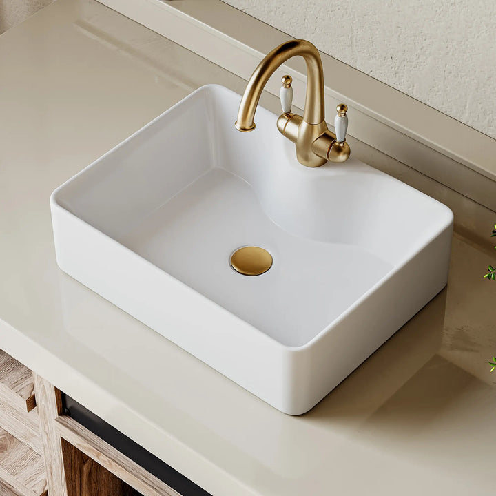 Double white ceramic vessel sinks with elegant gold faucets.