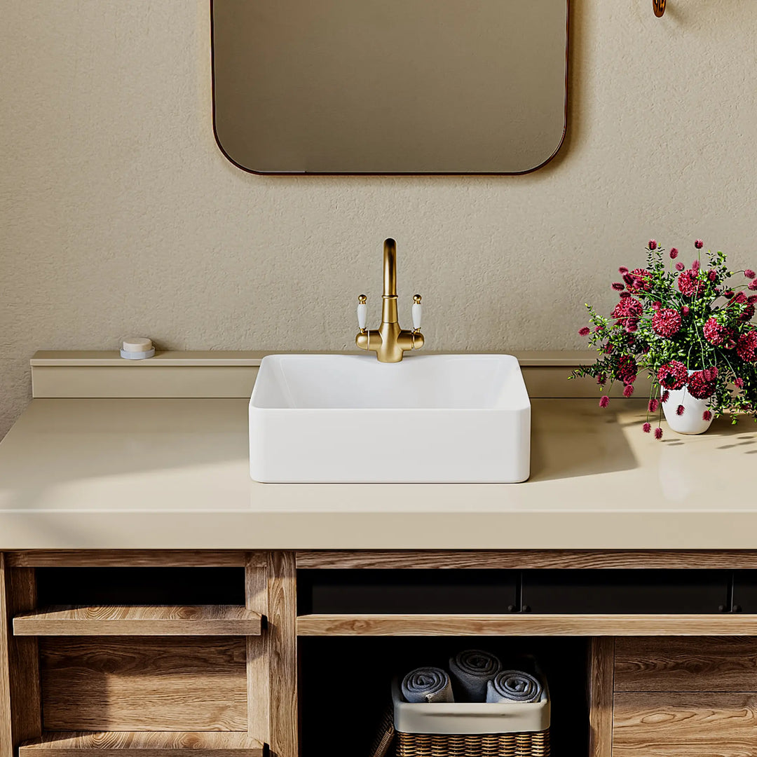 White rectangular ceramic vessel sink with gold faucet, front view.