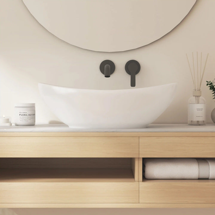 Glossy white curved ceramic vessel sink with matte black wall tap