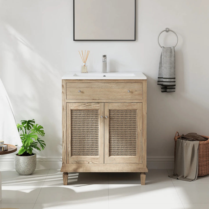 White bathroom vanity sink atop a light wood cabinet with rattan doors.