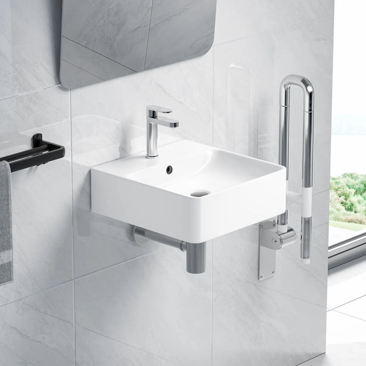 White wall-mounted sink with folding chrome grab bar.