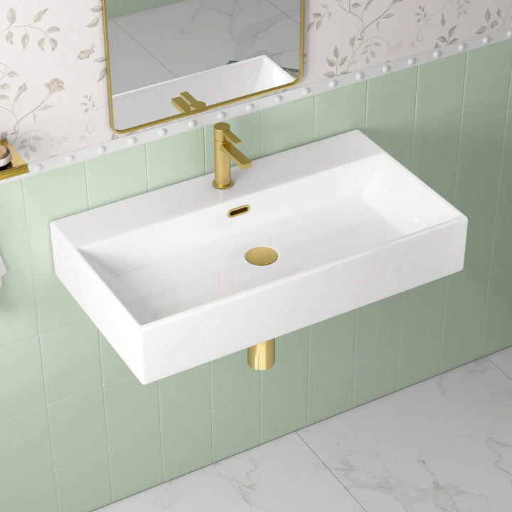 White rectangular wall-mount sink with single hole gold faucet.