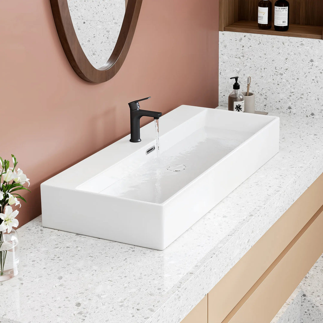 White rectangular ceramic vessel sink with black faucet